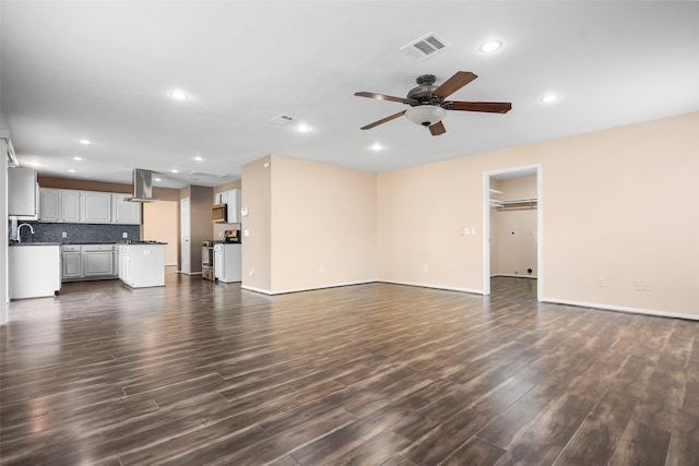 unfurnished living room with dark wood-type flooring, ceiling fan, and sink