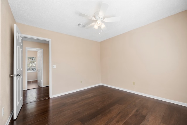 empty room featuring dark wood-type flooring, ceiling fan, and a textured ceiling