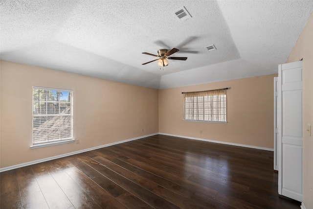 empty room featuring a textured ceiling, ceiling fan, plenty of natural light, and dark hardwood / wood-style flooring