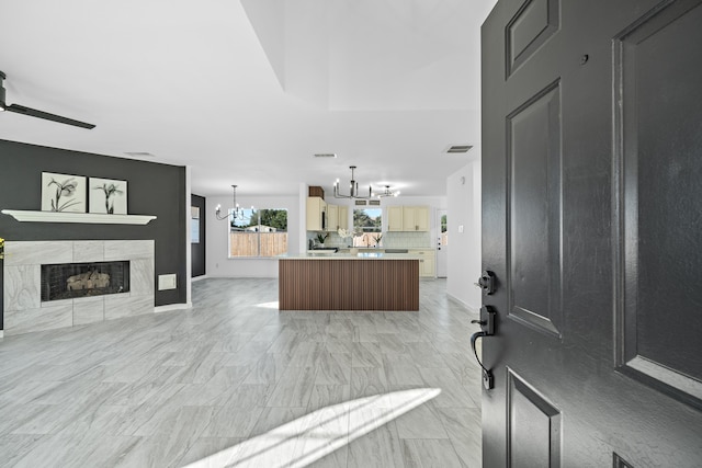 entrance foyer with ceiling fan with notable chandelier and a fireplace