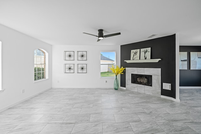 unfurnished living room with a tiled fireplace, a healthy amount of sunlight, and ceiling fan