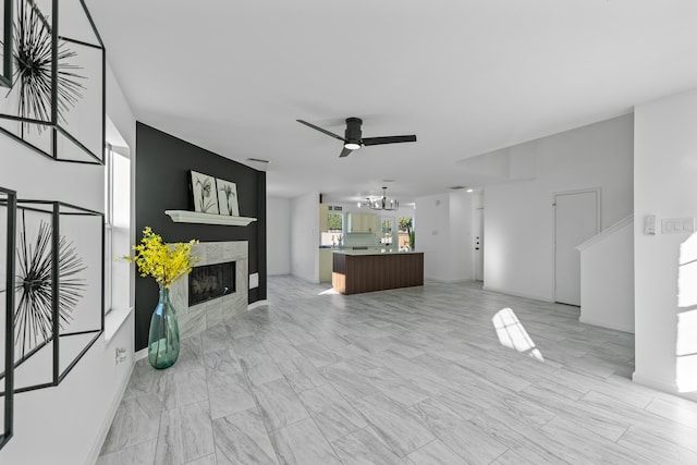 living room featuring a premium fireplace and ceiling fan with notable chandelier