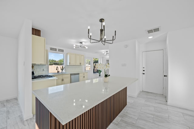 kitchen featuring cream cabinets, sink, hanging light fixtures, and a kitchen island