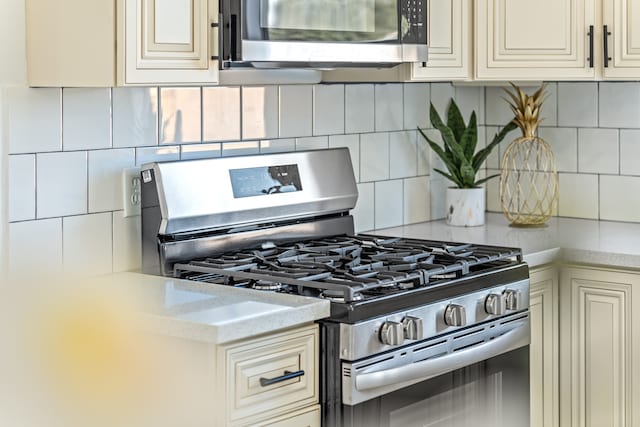 kitchen with backsplash, appliances with stainless steel finishes, and cream cabinetry