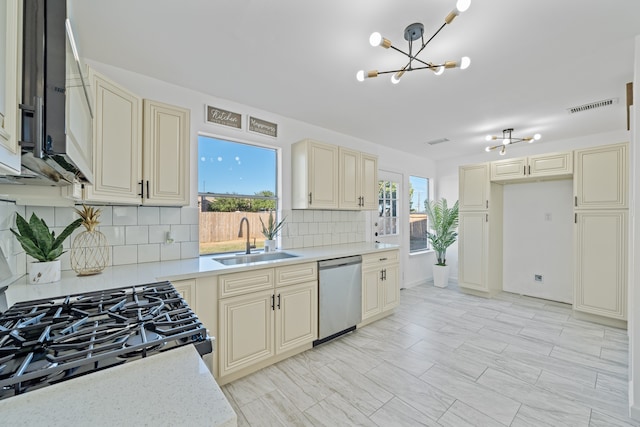 kitchen with a healthy amount of sunlight, stainless steel appliances, decorative backsplash, and sink