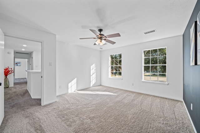 carpeted spare room featuring ceiling fan