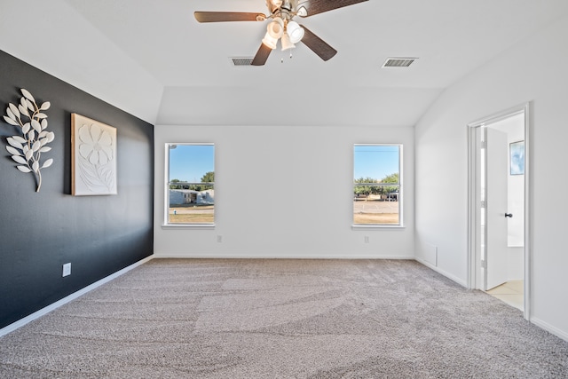 unfurnished room with lofted ceiling, ceiling fan, light colored carpet, and plenty of natural light