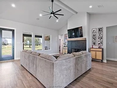 living room featuring hardwood / wood-style floors, lofted ceiling with beams, and ceiling fan