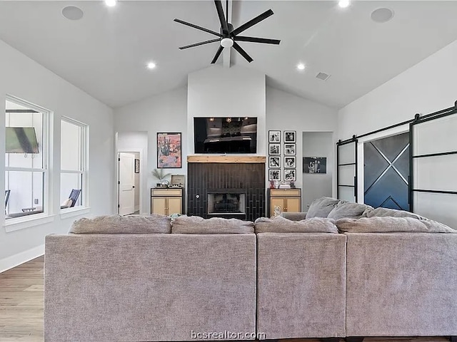 living room with lofted ceiling, a barn door, wood-type flooring, and ceiling fan