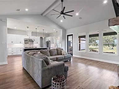 living room with dark hardwood / wood-style floors, beam ceiling, high vaulted ceiling, and ceiling fan