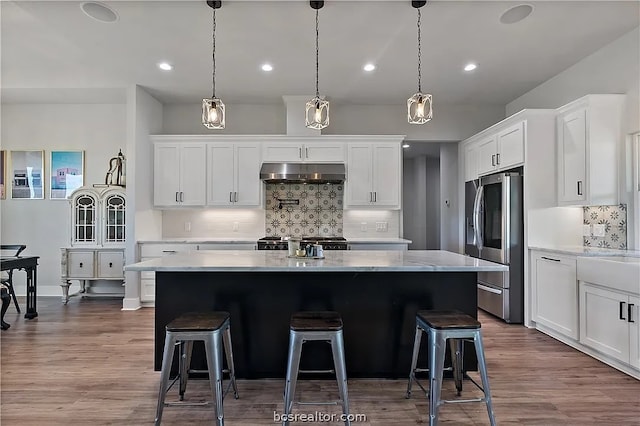 kitchen featuring hardwood / wood-style flooring, stainless steel appliances, a kitchen island, and white cabinets