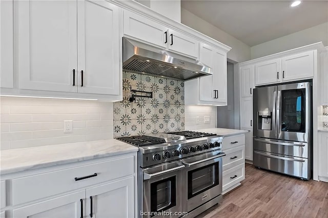 kitchen with backsplash, white cabinetry, light stone countertops, light hardwood / wood-style floors, and stainless steel appliances