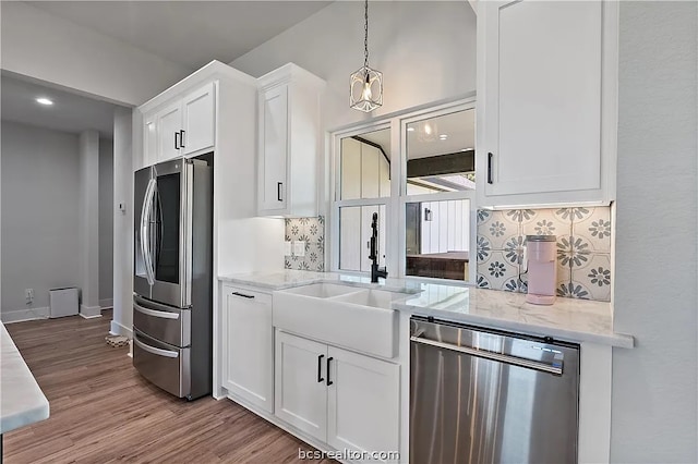 kitchen featuring decorative backsplash, appliances with stainless steel finishes, white cabinetry, light stone countertops, and sink