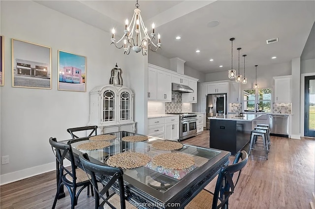 dining area featuring sink, a notable chandelier, and dark hardwood / wood-style flooring