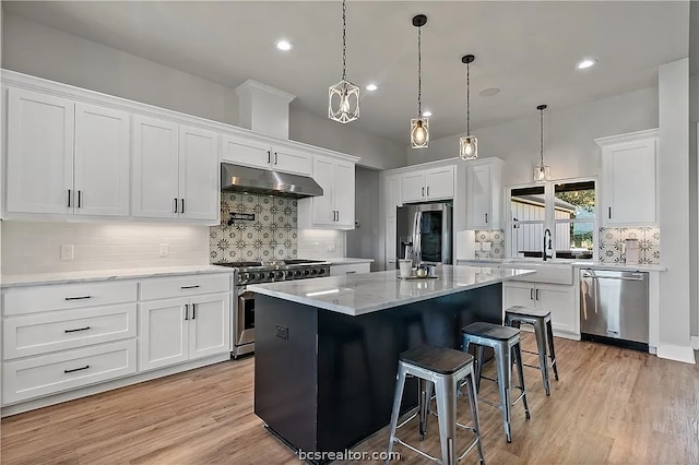 kitchen featuring a kitchen breakfast bar, stainless steel appliances, a center island, white cabinetry, and light hardwood / wood-style floors