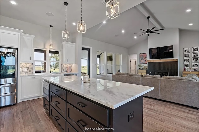 kitchen featuring backsplash, a center island, light hardwood / wood-style floors, white cabinets, and stainless steel refrigerator