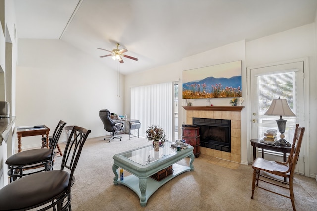 carpeted living room with a tiled fireplace, ceiling fan, and vaulted ceiling