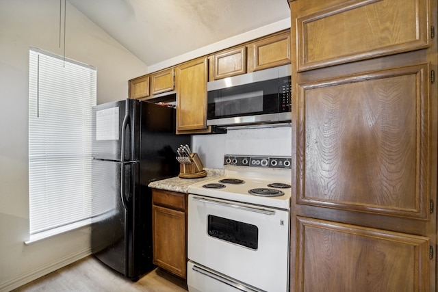 kitchen featuring white electric range, lofted ceiling, and black fridge