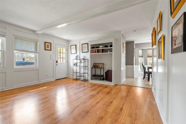 foyer entrance with a textured ceiling, light hardwood / wood-style flooring, and beam ceiling