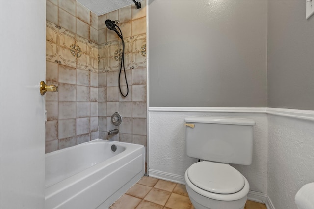 bathroom featuring a textured ceiling, tile patterned flooring, tiled shower / bath combo, and toilet