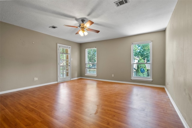 spare room with a textured ceiling, ceiling fan, and light hardwood / wood-style floors