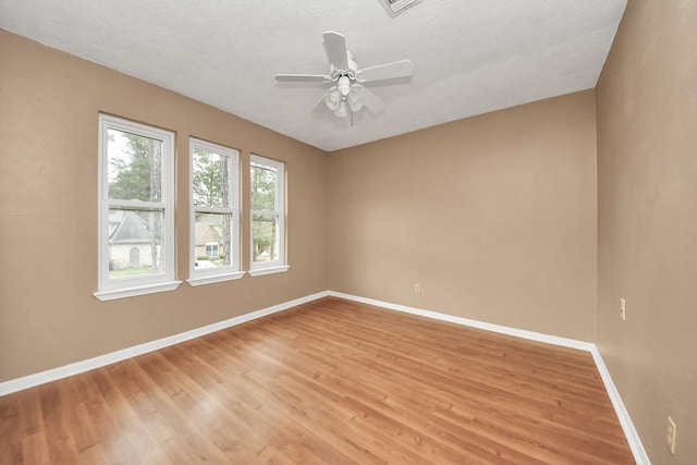 empty room with ceiling fan, light hardwood / wood-style flooring, and a textured ceiling