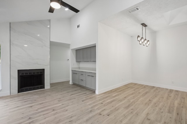 unfurnished living room with light hardwood / wood-style flooring, a textured ceiling, a large fireplace, and ceiling fan