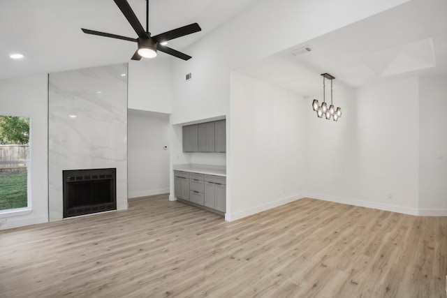 unfurnished living room with ceiling fan, heating unit, light hardwood / wood-style flooring, and a tile fireplace