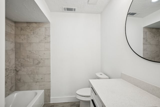 full bathroom featuring tiled shower / bath, a textured ceiling, hardwood / wood-style flooring, toilet, and vanity