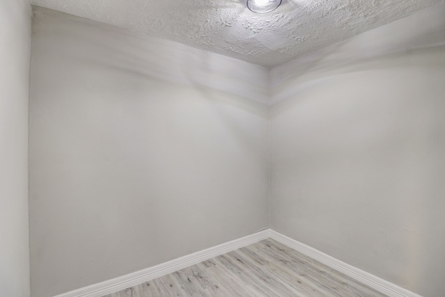 spare room featuring light hardwood / wood-style floors and a textured ceiling