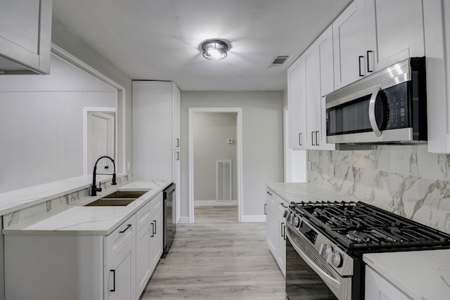 kitchen with light stone countertops, sink, backsplash, stainless steel appliances, and white cabinets