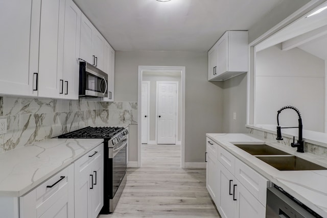 kitchen featuring white cabinetry, light stone counters, appliances with stainless steel finishes, and light wood-type flooring