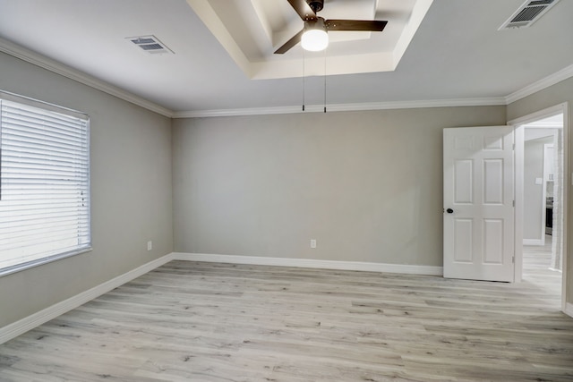 unfurnished room with crown molding, a raised ceiling, light wood-type flooring, and ceiling fan