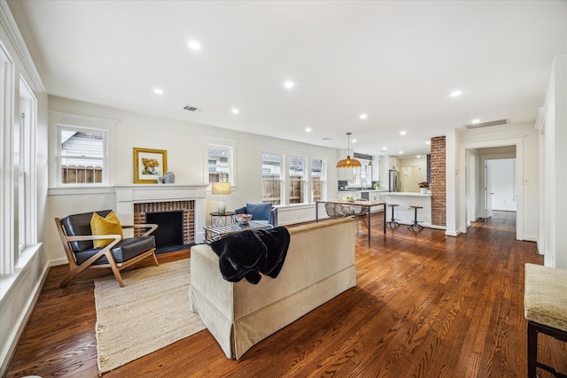 living room featuring dark wood-type flooring and a brick fireplace