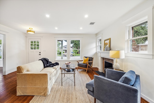 living room featuring a brick fireplace, a healthy amount of sunlight, and hardwood / wood-style flooring