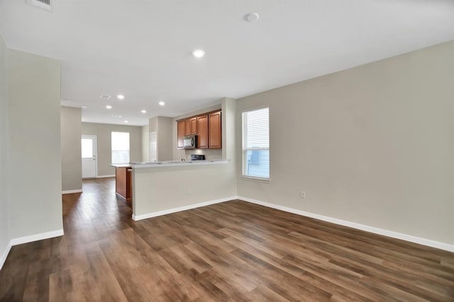 kitchen with kitchen peninsula, a breakfast bar, and dark hardwood / wood-style flooring