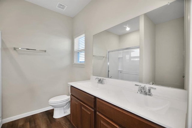 bathroom featuring a shower with door, vanity, hardwood / wood-style floors, and toilet