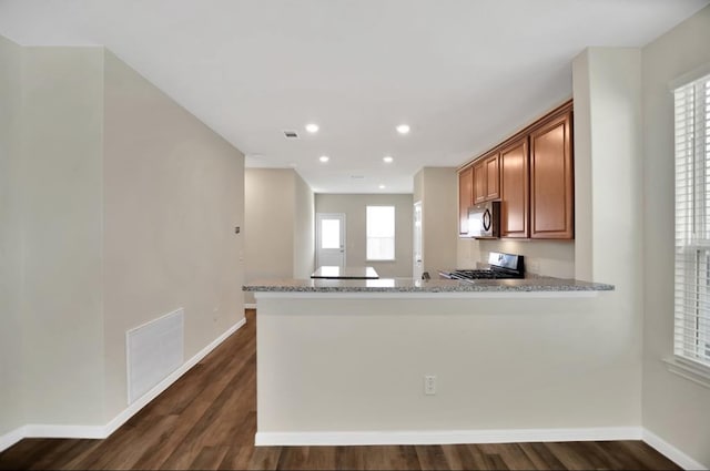 kitchen featuring appliances with stainless steel finishes, kitchen peninsula, light stone countertops, and dark wood-type flooring