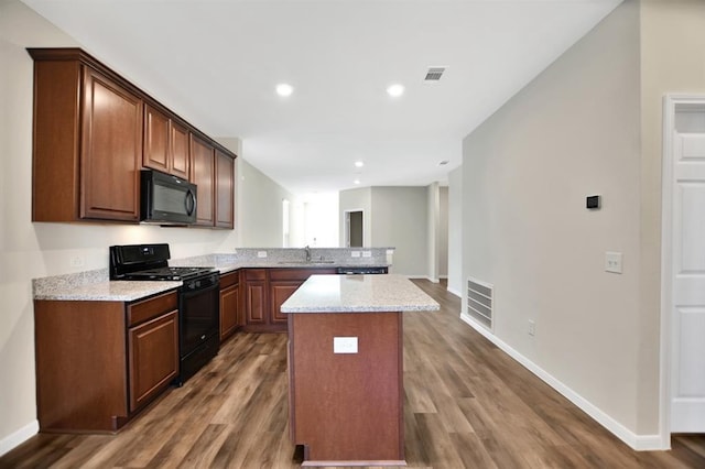 kitchen with sink, black appliances, dark wood-type flooring, and a kitchen island