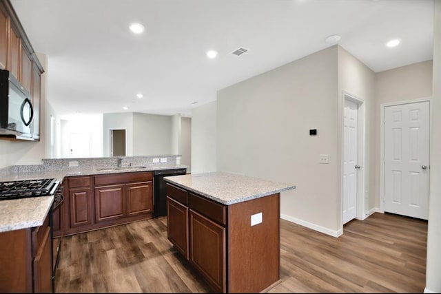 kitchen with sink, black appliances, dark wood-type flooring, and a kitchen island