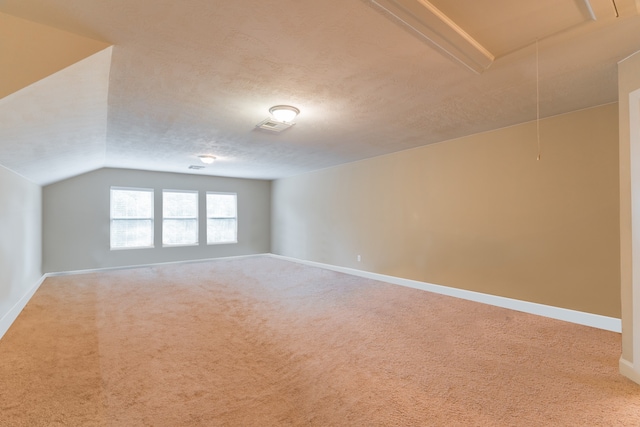 additional living space featuring lofted ceiling, a textured ceiling, and carpet flooring