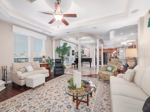 living room with dark wood-type flooring, ornate columns, and a raised ceiling