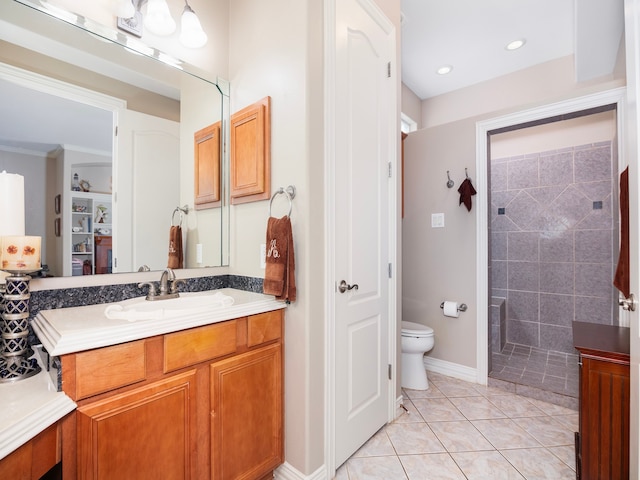 bathroom with toilet, vanity, tile patterned floors, and tiled shower