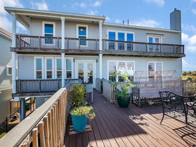 rear view of property with french doors, a wooden deck, and a balcony