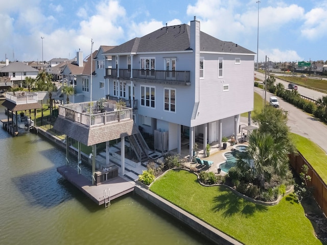 back of house featuring a fenced in pool, a patio, a water view, and a balcony