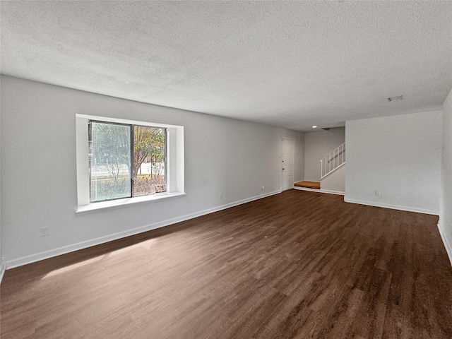 empty room featuring a textured ceiling and dark hardwood / wood-style floors