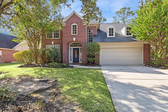 traditional-style home with brick siding, a garage, a front yard, and concrete driveway