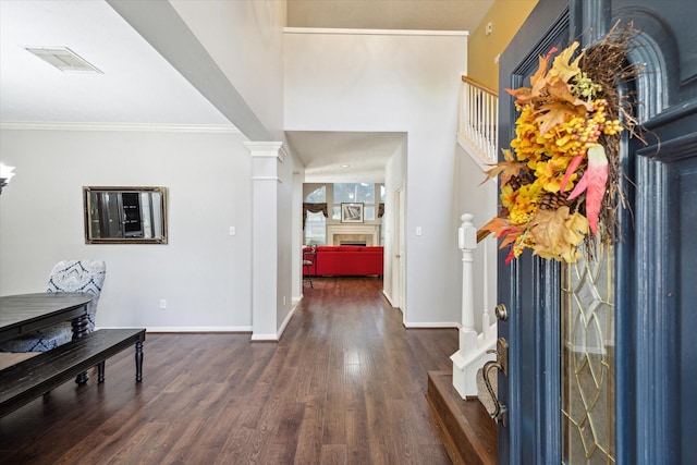 foyer with visible vents, ornamental molding, wood finished floors, a fireplace, and baseboards