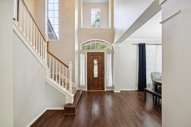 foyer with a high ceiling, crown molding, and dark wood-type flooring