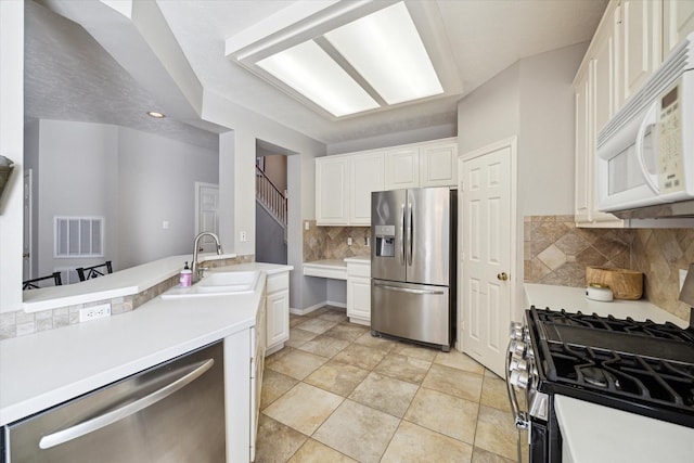 kitchen with light tile patterned floors, backsplash, white cabinets, appliances with stainless steel finishes, and sink